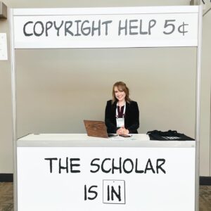 A woman positioned at a table with a sign that says "Copyright Help 5 cents," ready to assist individuals with copyright questions.